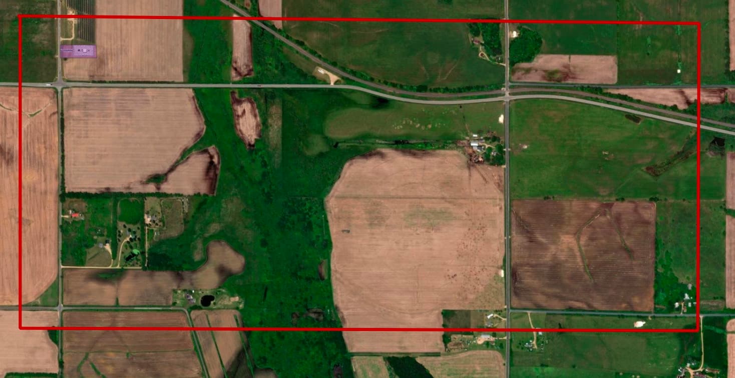 Aerial view showing the ~0.25–1.5 acre Hay River site footprint outlined in purple, set against the ~700-acre red outline of a typical hyperscale facility, roughly 350 times larger
